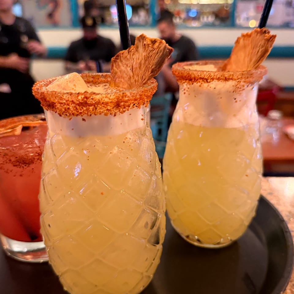 Cocktails in pineapple-shaped glasses with chili rims
