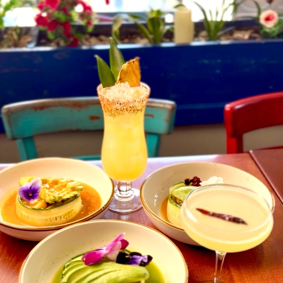 Trio of aguachiles with avocado and orchids beside a pineapple margarita.
