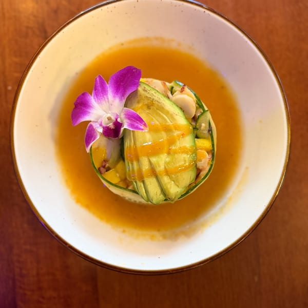 Torre de mariscos with sliced avocado and orchid in a bright mango broth.